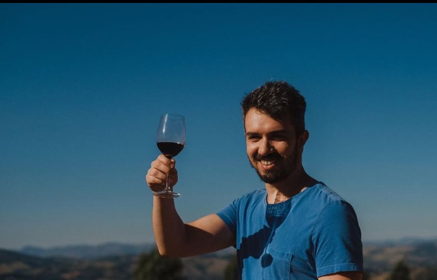 Brinde com taça de vinho tinto no alto do vinhedo